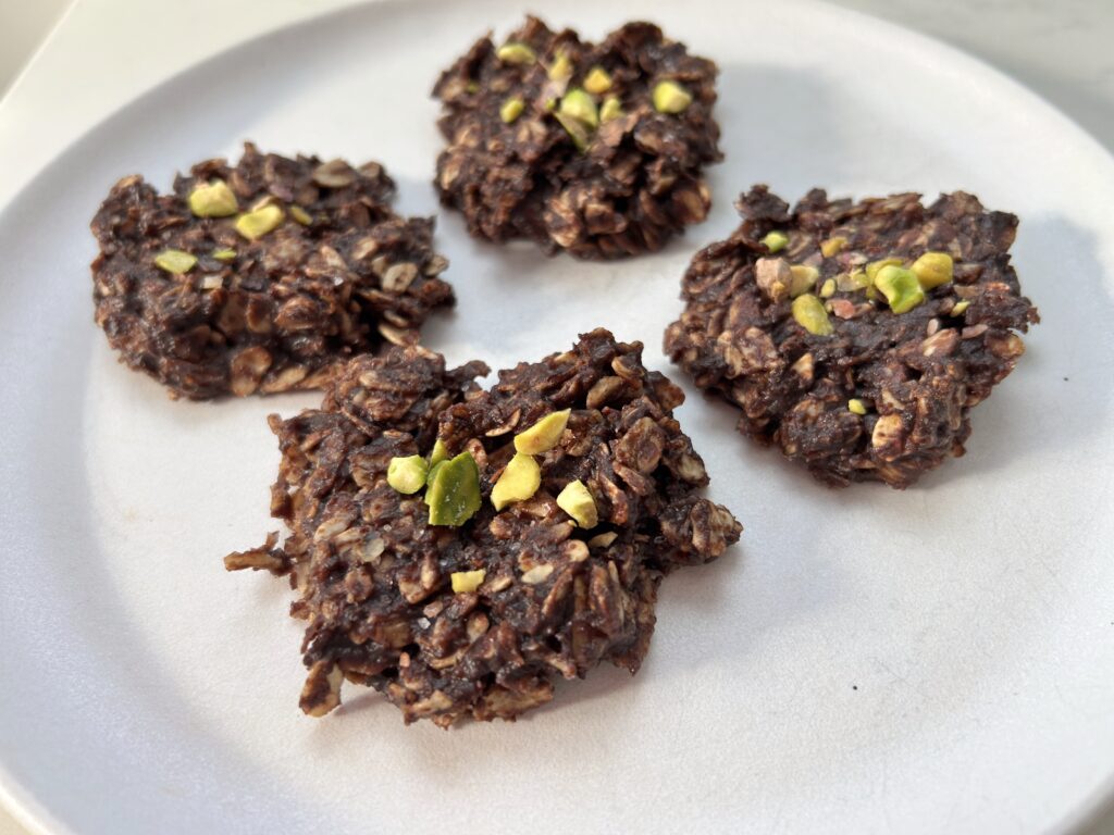 Fertility boosting no-bake chocolate cookies topped with chopped pistachios, made with raw cacao, almond butter, coconut oil, oats, and dark chocolate chips